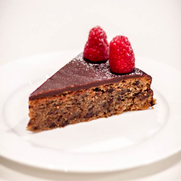 Slice of Chocolate Torta with 2 raspberries on top.