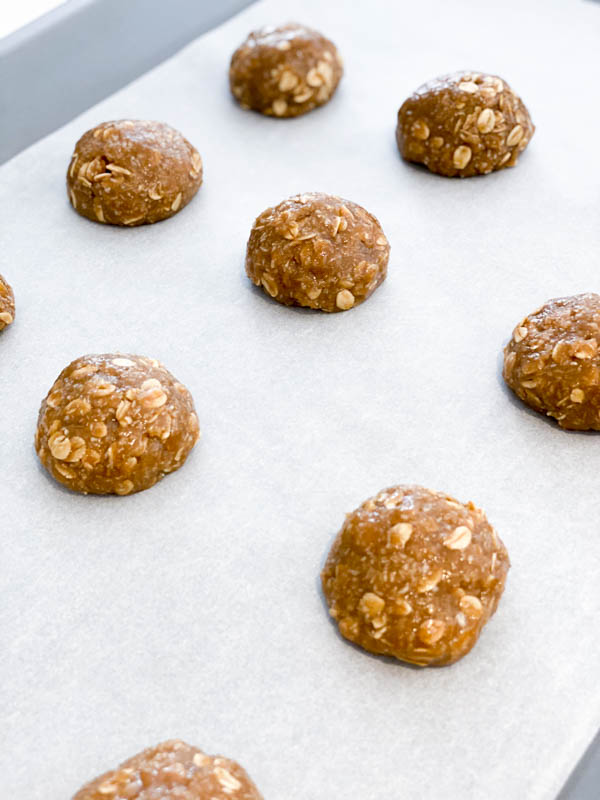 Raw Anzac Biscuit Dough rolled into balls on a baking tray ready for the oven.