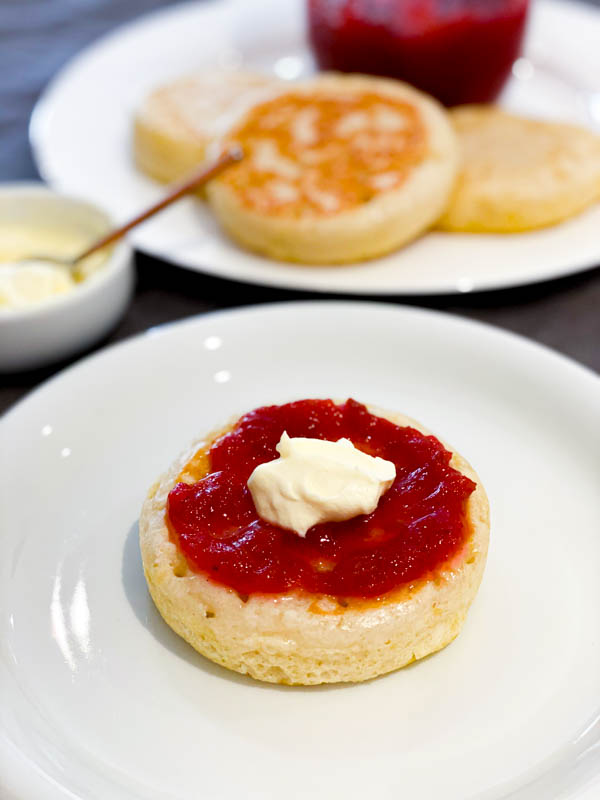 Easy Rhubarb Compote on top of a crumpet with cream on top in the foreground, with more crumpets in the background.