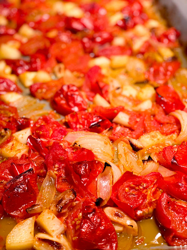 Roasted and caramelised tomatoes, onions and garlic on oven tray.