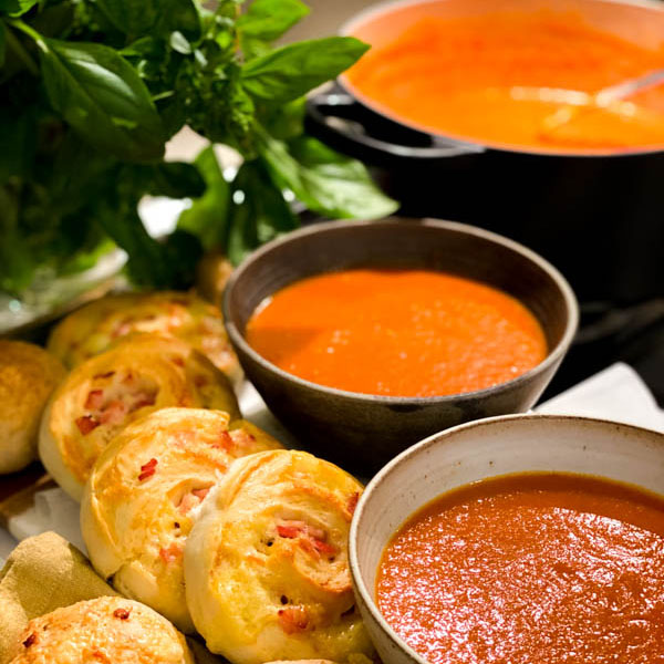 Close up of Roasted Tomato Soup in 2 bowls with Cheese and Bacon Scrolls.