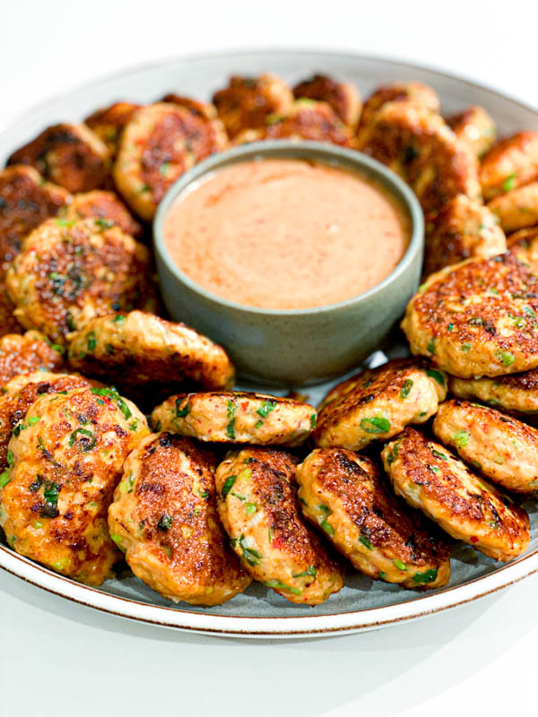 A platter of Thai Fish Cakes on a platter with a bowl of Sweet Chilli Mayo in the centre.