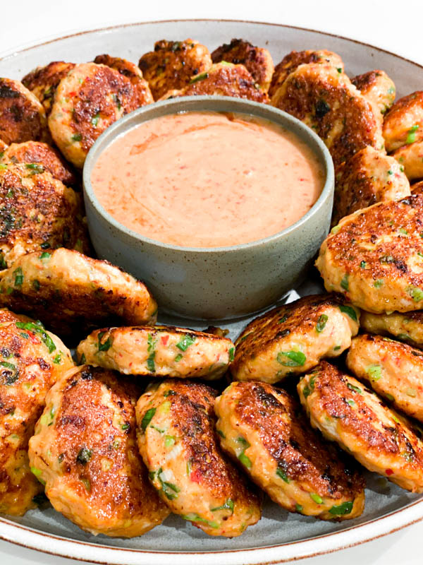 Close up of the Thai Fish Cakes with a bowl of Sweet Chilli Mayo.