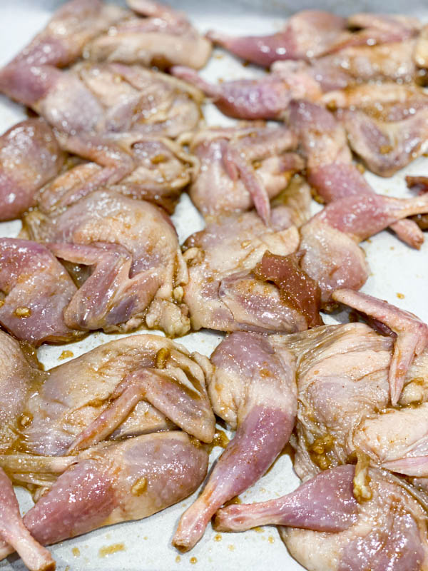 The Butterflied Quail laid out on an oven tray lined with baking paper, ready for the oven.