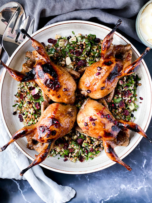 Looking down onto a platter of Cypriot Grain Salad with 4 whole quail on top.