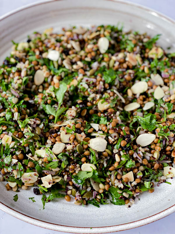 Looking down onto a flat white ceramic platter with the Cypriot Grain Salad spread out on the platter.