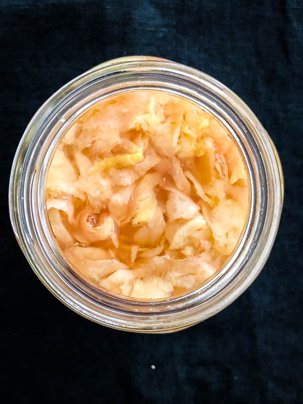 Looking down into a jar of Easy Pickled Ginger with a black background.