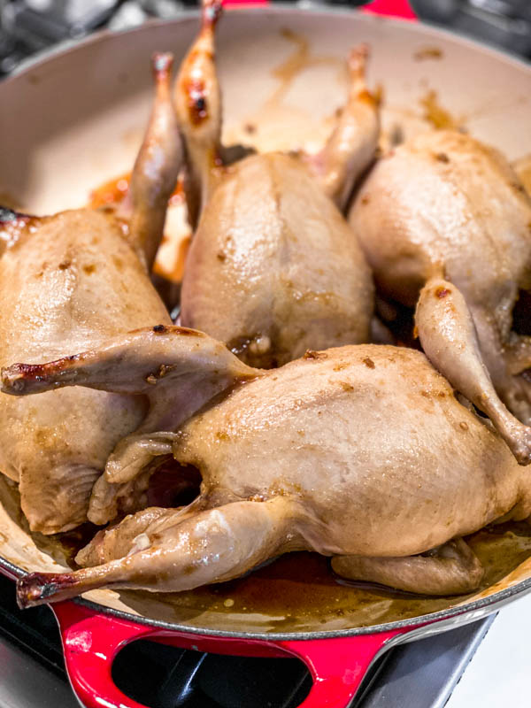 The marinated Roasted Pomegranate Quail in a pan, ready to go into the oven