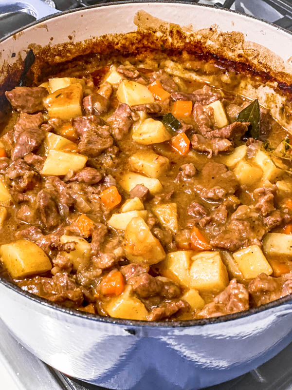 A blue Le Creuset Dutch oven filled with Beef and Vegetable filling, cooked and ready to be chilled.