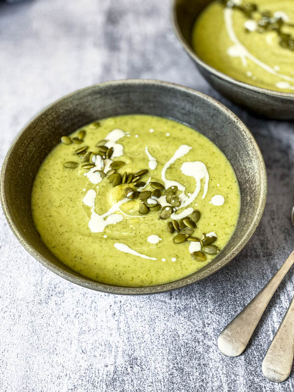 A bowl of Broccoli Soup is in the centre with another bowl just off to the top right of the photo.