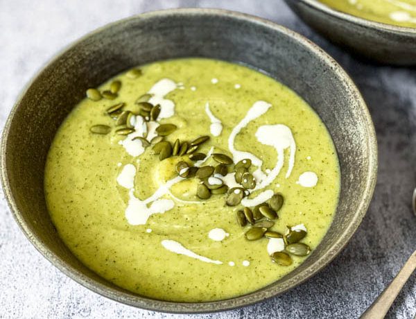 A bowl of Broccoli Soup on a grey bench top with another bowl behind it.