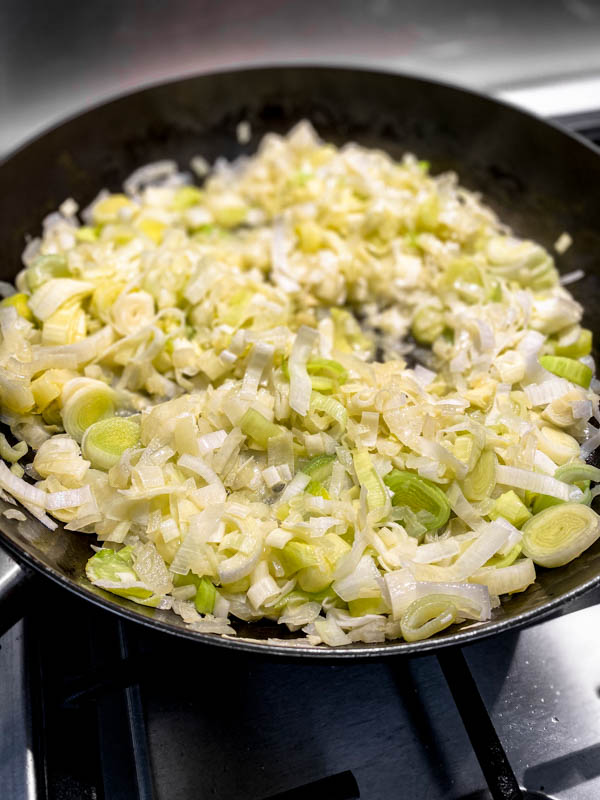 The sauteed and softened chopped onions, leeks and garlic in a frying pan ready for the other ingredients to be added.