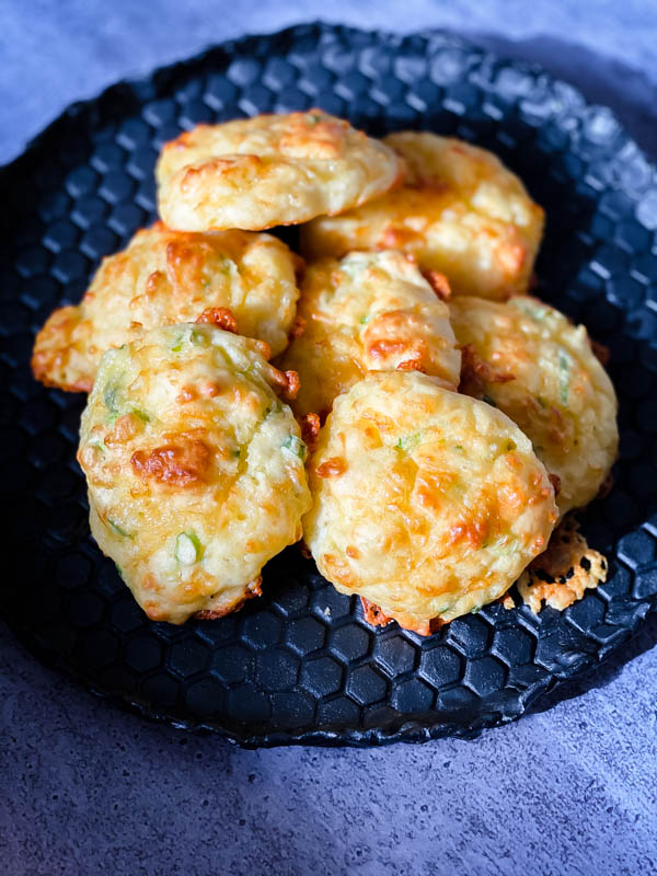 A plate of Cheese Puffs. The plate is black with a beehive pattern on it.