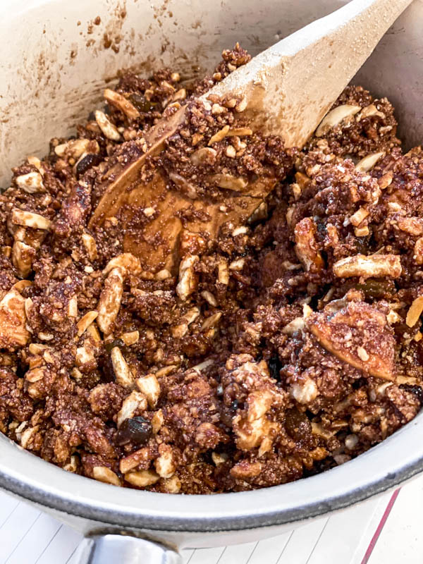 The dry ingredients (biscuits, nuts, sultanas and coconut) are now mixed into the melted cocoa, butter and sugar.