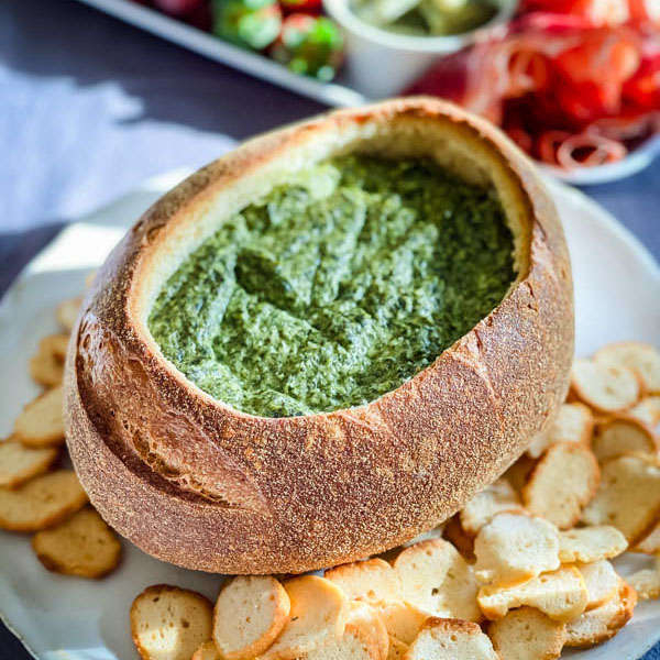 Close up of the Spinach Cob Loaf Dip with round bagel croutons surrounding it.