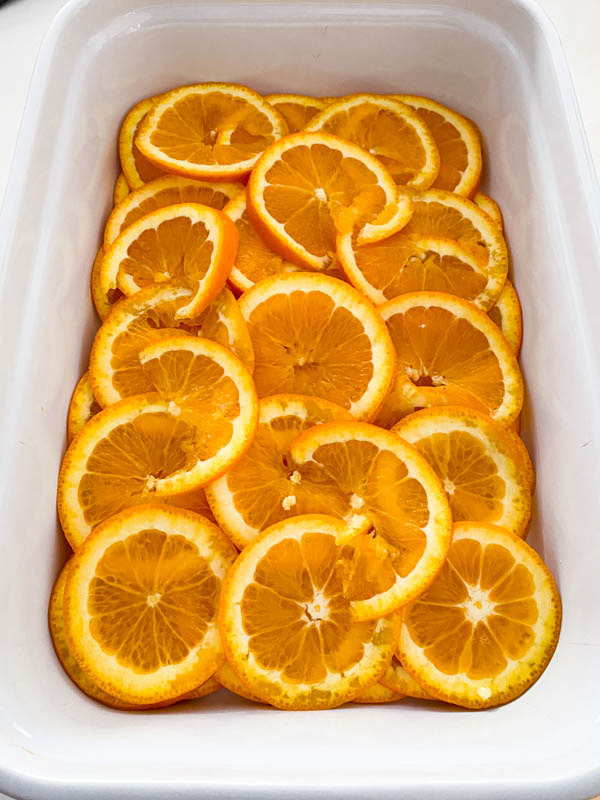 The orange slices are placed in layers in a large rectangle baking dish.