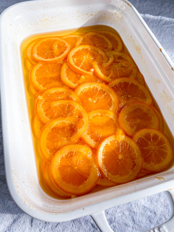 The orange slices are now out of the oven and softened. They are cooling in the syrup.