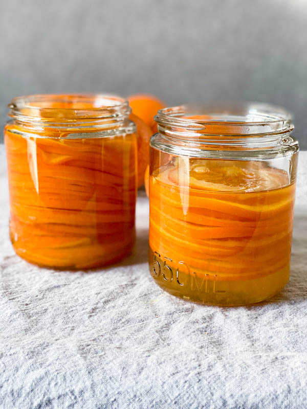 A side view of the jars of confit orange slices in their syrup.