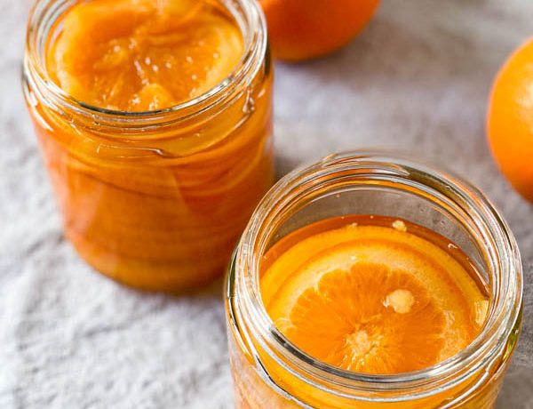 A close up looking down into the jars of confit orange slices.