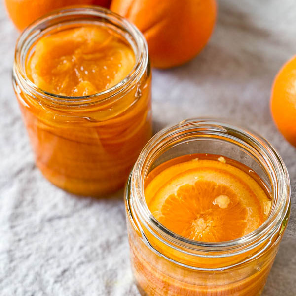 A close up looking down into the jars of confit orange slices.