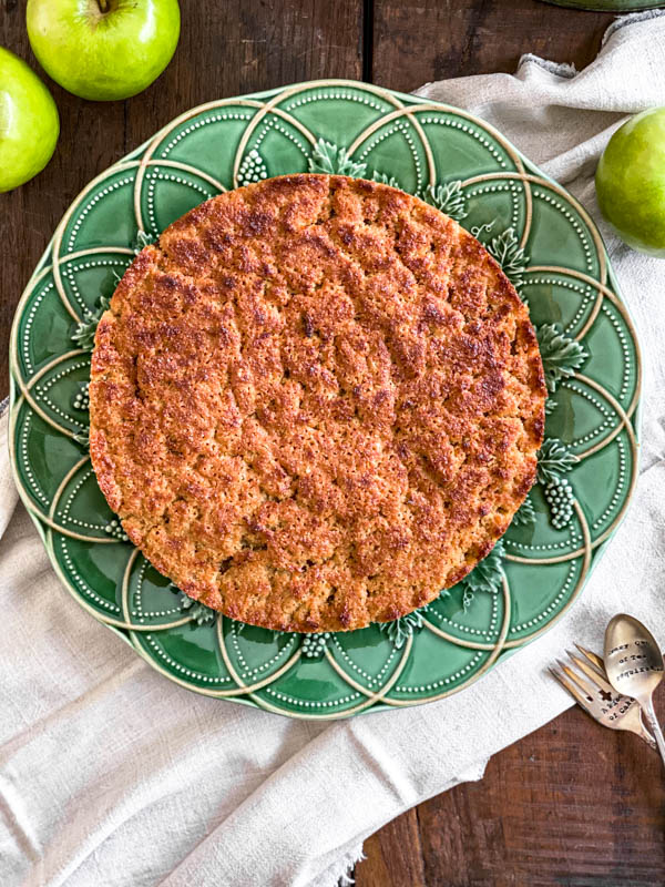 Looking down onto the Lumberjack Cake so you can see the coconut topping. The cake is on a green platter on a wooden table.