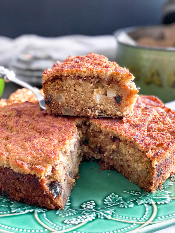 The cake has a slice removed from it so you can see the inside of the cake, showing bits of apple and dates and a very moist, dense crumb.