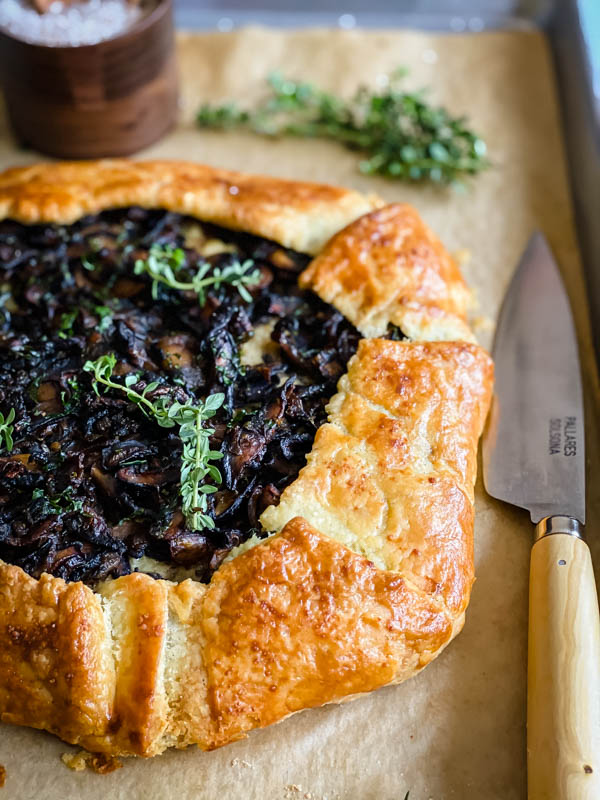 Close up of the now cooked galette. The pastry is golden and flaky. There is a kitchen knife beside the galette.