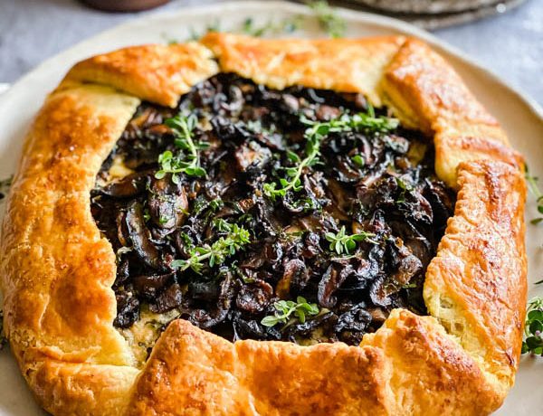 Close up of the golden pastry wrapped galette. It is decorated with sprigs of thyme and ready to be served.