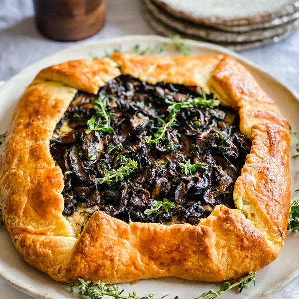 Close up of the golden pastry wrapped galette. It is decorated with sprigs of thyme and ready to be served.