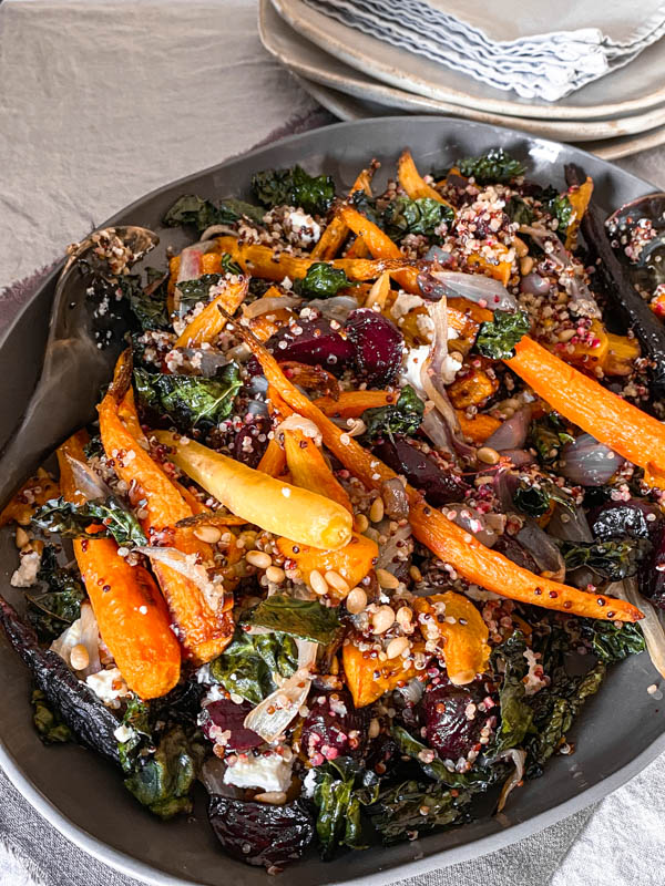 A close up of the Roasted Vegetable, Quinoa and Feta Salad with plates and napkins behind it.