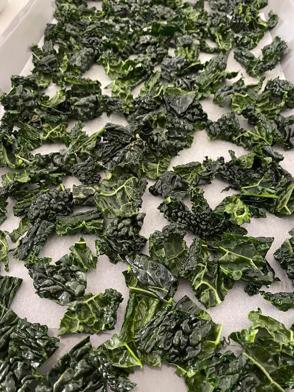 Chopped kale spread out on a baking paper lined baking tray.