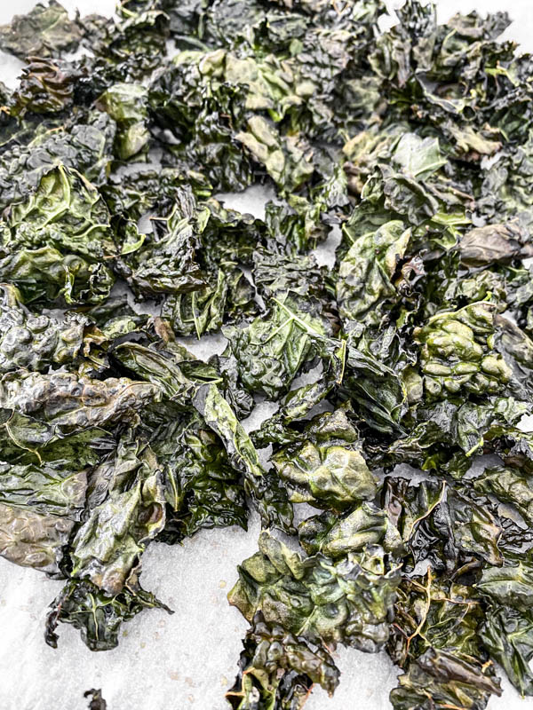 Crispy kale pieces just out of the oven on the baking tray.