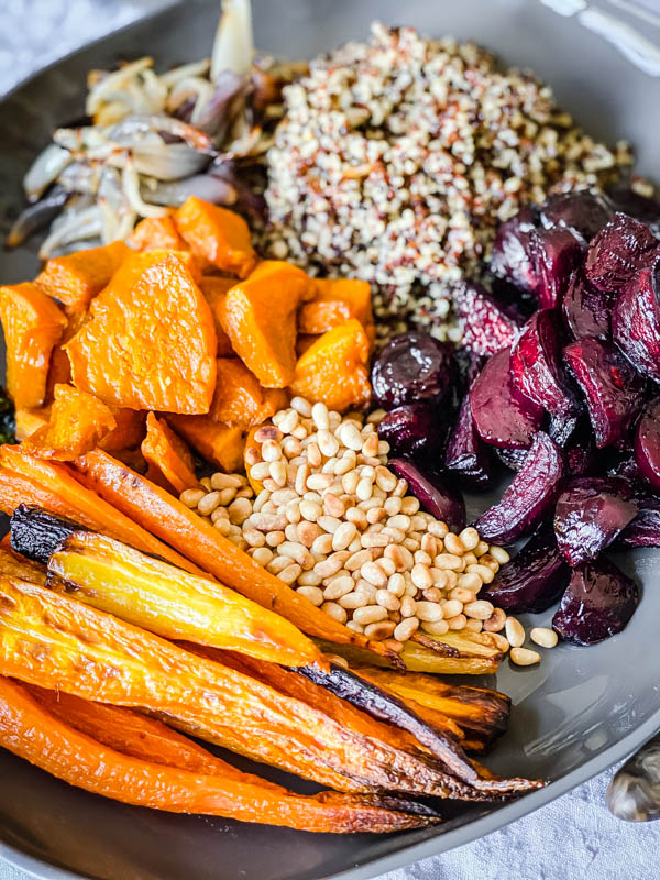 A platter with all the components of the salad separately placed and ready to be tossed together - roasted baby carrots, baby beetroots, pumpkin and onion, along with toasted pine-nuts and cooked quinoa.