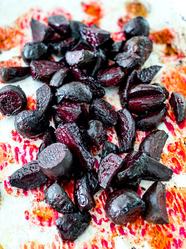 Roasted baby beetroot on an oven tray lined with parchment paper.