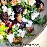 The Roast Beetroot, Goats Cheese and Walnut Salad is dressed and on a white platter with rocket (arugula) leaves.