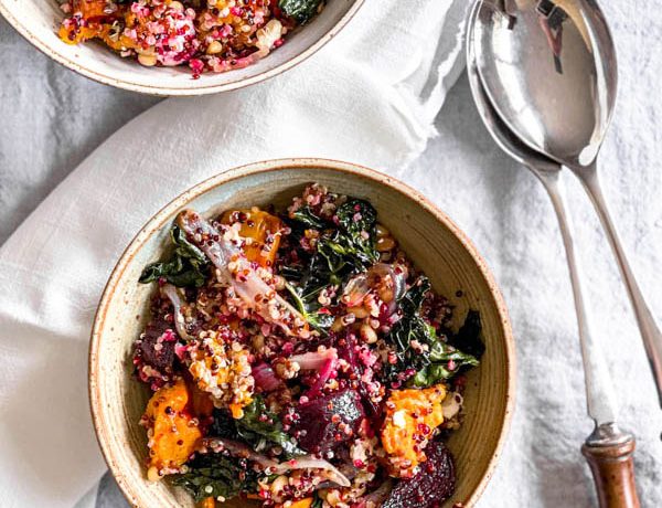 Close up of a serving sized bowl of salad with serving salad servers next to it and another bowl in the background.