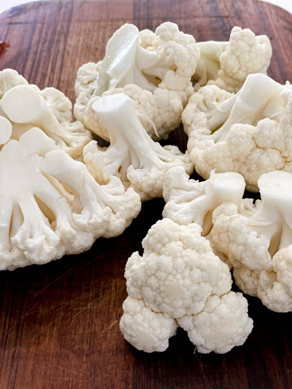 Cauliflower florets on a wooden chopping board.