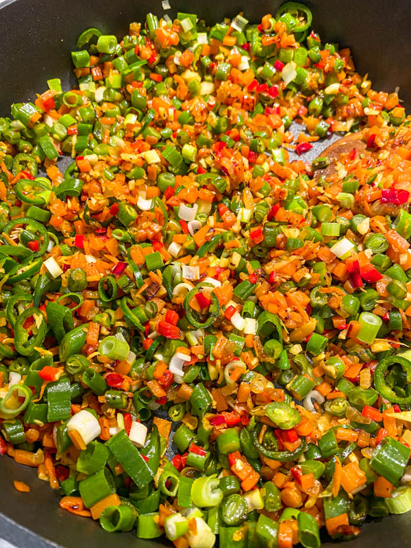 All the vegetables except the cauliflower is sauteeing in a frying pan.