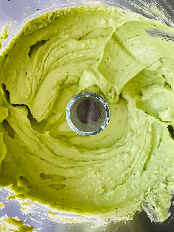 Looking down into the food processor bowl with the blended avocado mixture showing how smooth it is.