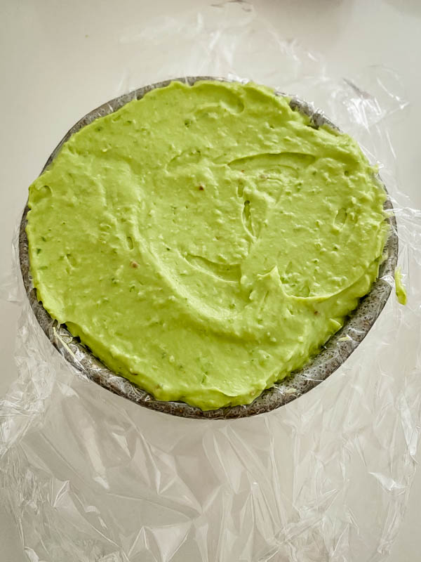 The avocado pate is in the small bowl that has been lined with cling wrap.