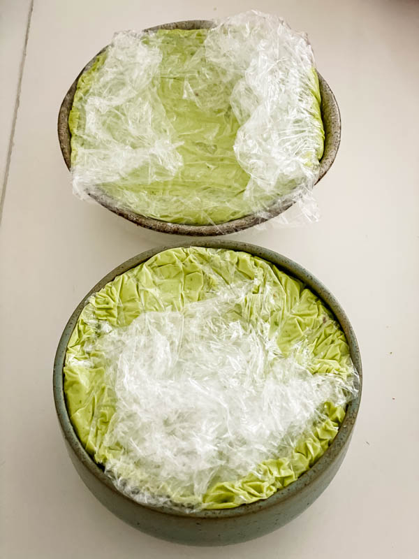 This shows both small bowls now filled with the avocado pate and covered in cling wrap. The bowls are now ready to be placed in the fridge.