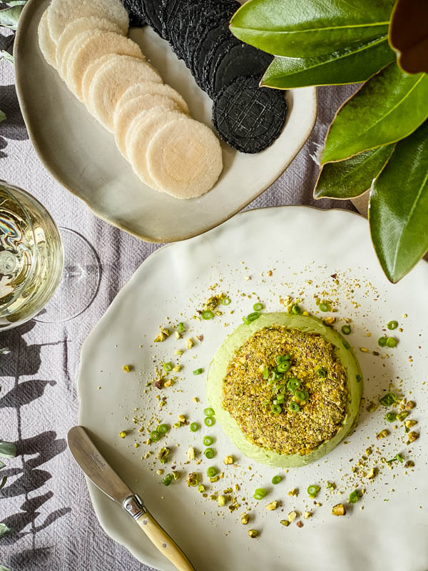 Looking down onto the table with the Avocado Pistachio Pate, crackers and wine on it.