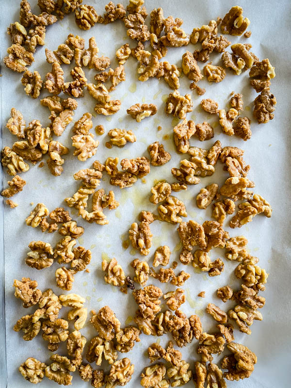 The candied walnuts are spread out and cooling on baking paper.
