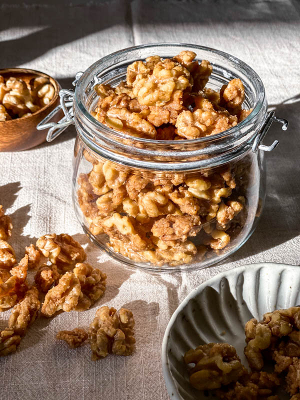 The jar of Candied Walnuts are sitting in the sunlight.