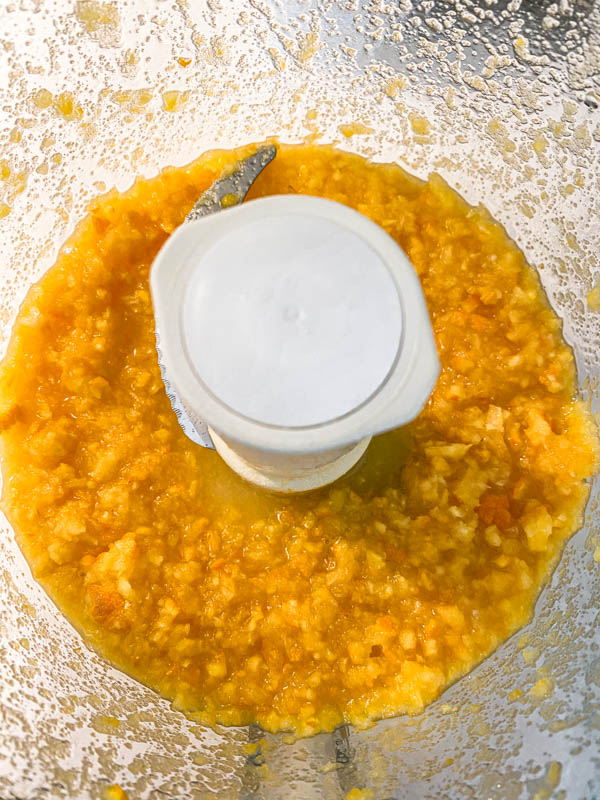 Looking into the bowl of the food processor where the orange and sugar are now processed to a pulpy, finely chopped consistency.