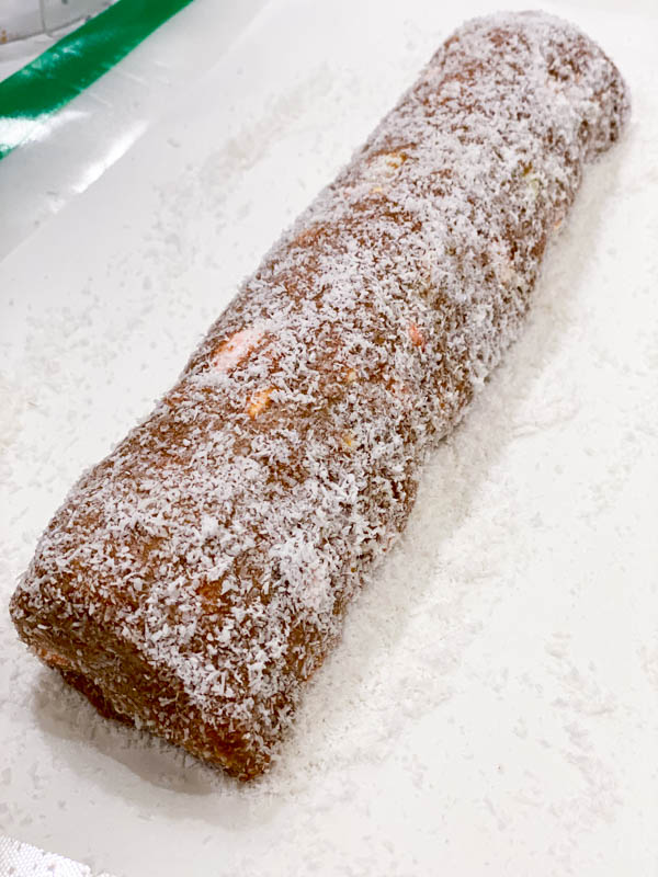 The cake mixture is now shaped into a log and rolled in coconut.