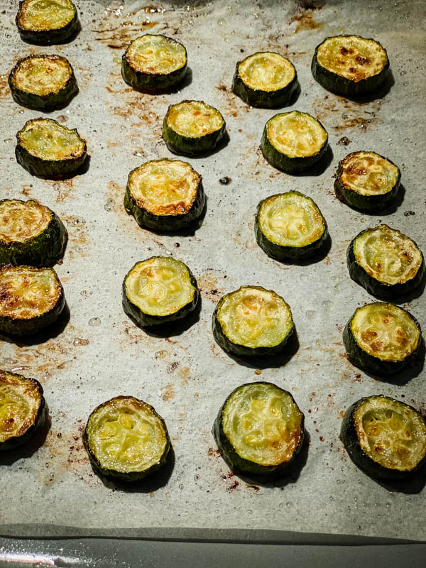 Slices of roasted zucchini on a baking tray.