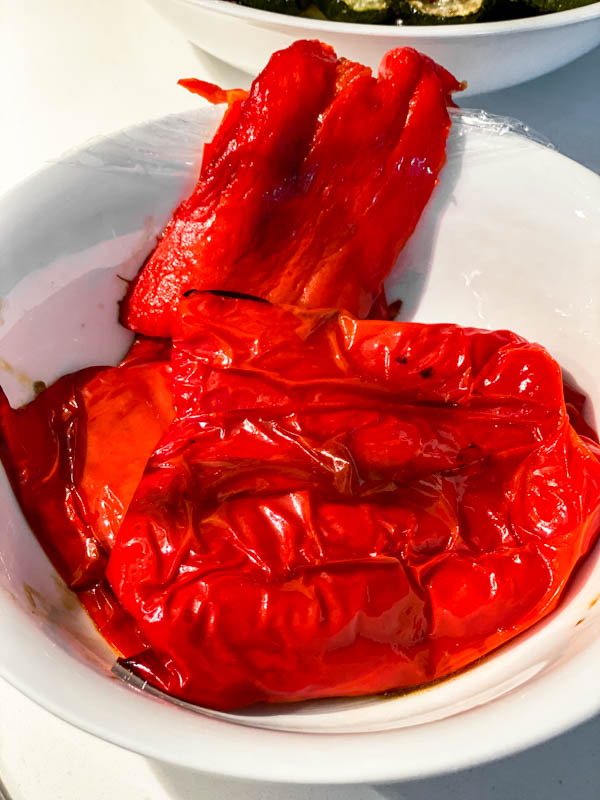 A bowl with the roasted red pepper ready to have the skin peeled off.