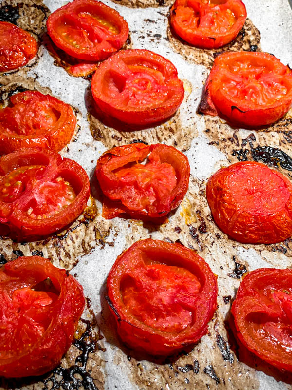 The roasted slices of tomato on an oven tray.