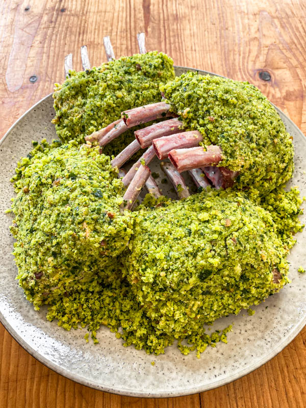 The lamb racks have now been covered with the herb crust and are sitting on a plate, ready to be cooked or refrigerated.